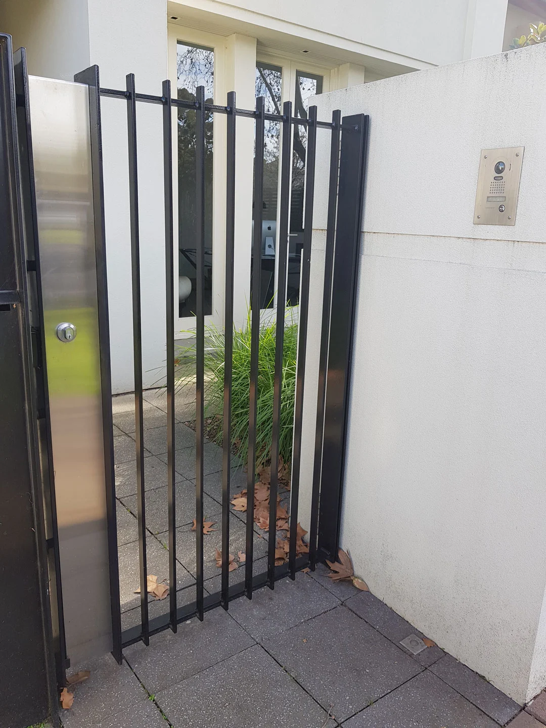 Black steel pedestrian gate beside a white house