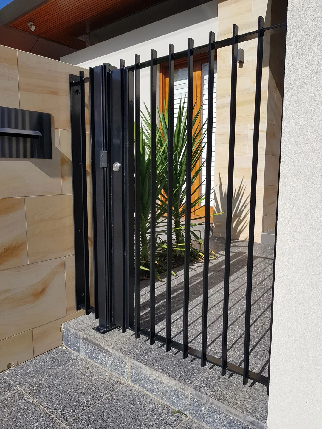 Black steel entry gate between stone columns