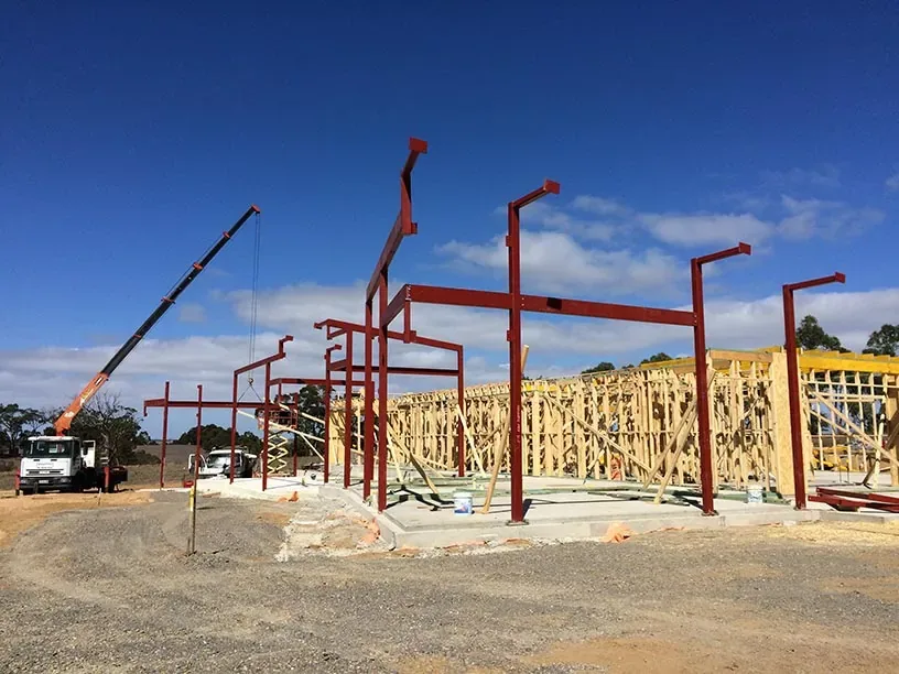 Red structural steel framing installed beside timber framing