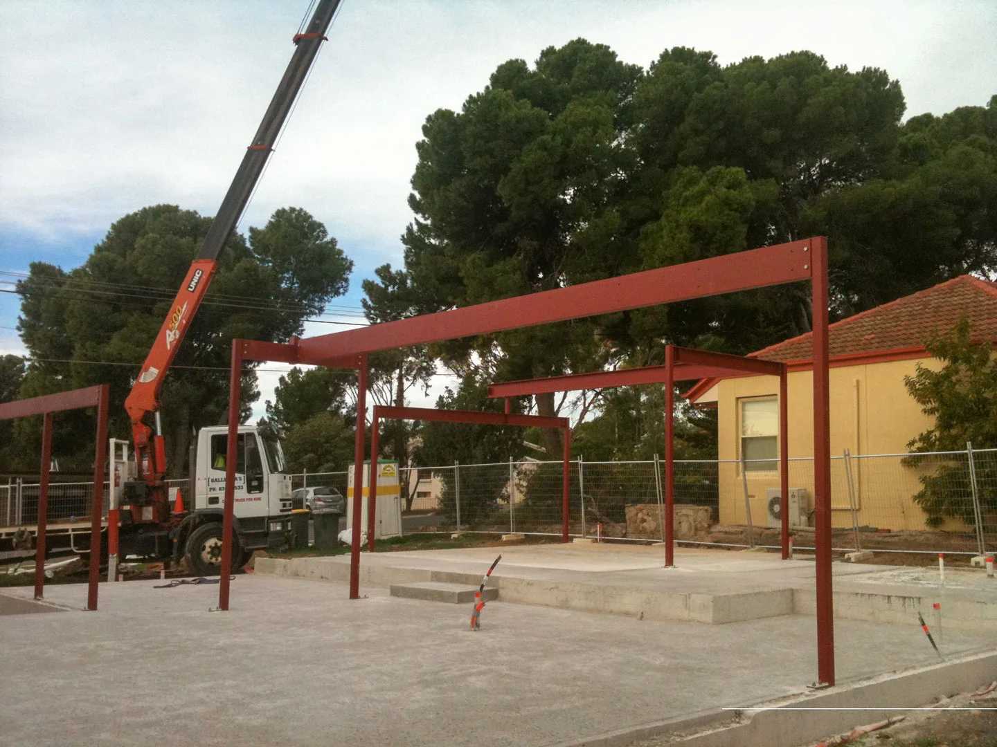 Galletta's crane truck with its crane extended beside structural steel framing on site
