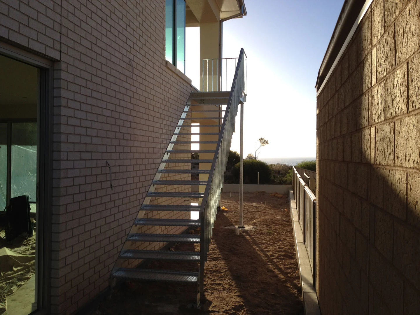 Exterior steel staircase installed between brick walls